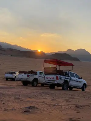 two trucks parked in the desert with the sunset in the background at Wadi rum desert sky in Wadi Rum