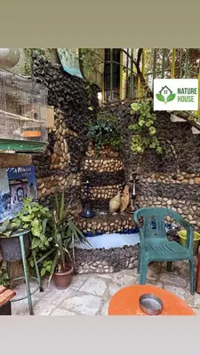 a green chair sitting in front of a stone wall at بيت الطبيعة nature house in Jerash