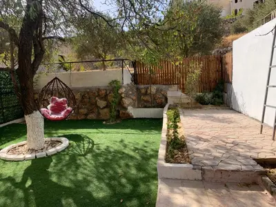 a garden with a tree and a stone wall at Tayoon Host in Jerash