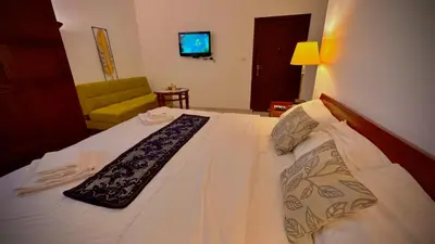 a bedroom with a bed with a white bedspread and a chair at Tell Madaba in Madaba