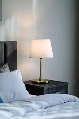 a lamp on a night stand next to a bed at Abdali Views Apartments in Amman