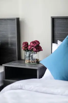 a vase of flowers on a table next to a bed at Abdali Views Apartments in Amman