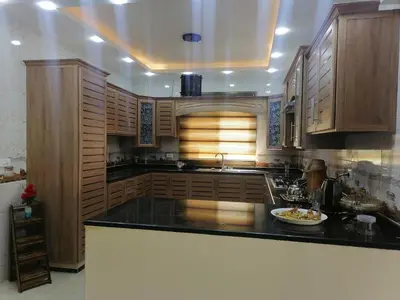a kitchen with wooden cabinets and a black counter top at Petra Guests home in Wadi Musa
