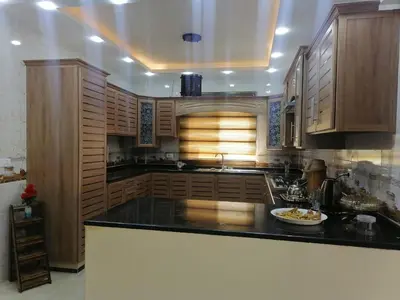 a kitchen with wooden cabinets and a black counter top at Petra Guests home in Wadi Musa