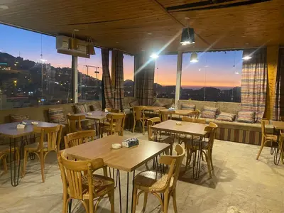a restaurant with tables and chairs and a large window at Raqeem Hotel in Wadi Musa