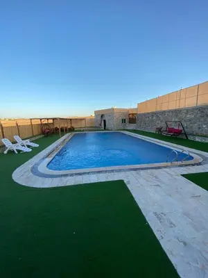 a swimming pool in a yard with green grass at Fog Mountain Hotel Rooms & sauna in Jaḩrāʼ