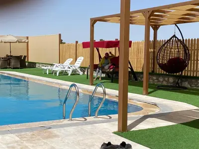 a swimming pool with a hammock and a swing at Fog Mountain Hotel Rooms & sauna in Jaḩrāʼ