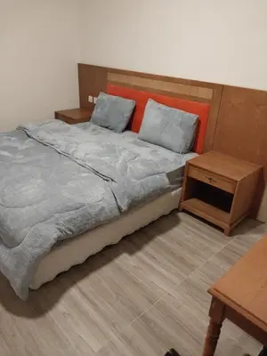 a bedroom with a large bed and a table at Fog Mountain Hotel Rooms & sauna in Jaḩrāʼ