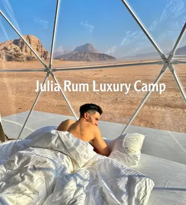 a man laying in bed in the desert at JULIA RUM lUXURY CAMP in Wadi Rum