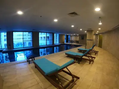 a swimming pool in a building with tables and benches at Al Fares Luxury furnished Apartment-Damac Tower in Amman