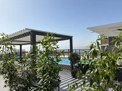 a swimming pool with a pergola and some plants at Mass Boutique hotel in Aqaba