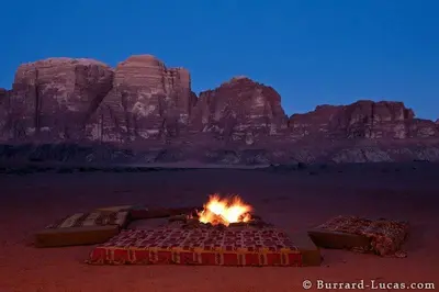 a camp fire in the desert with mountains in the background at Mad Mix camp in Wadi Rum