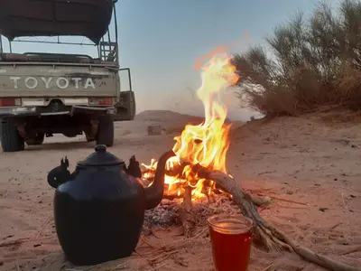 a campfire with a teapot and a pot on fire at Mad Mix camp in Wadi Rum