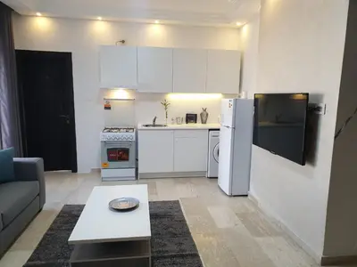 a small kitchen with a white refrigerator and a table at Deir Ghbar-Studio in Amman