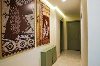 a hallway with paintings on the wall and a green door at Sandra Hotel in Amman