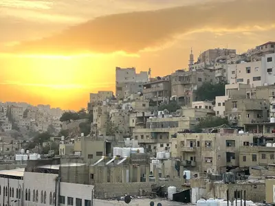 a group of buildings on a hill with the sunset at Sandra Hotel in Amman