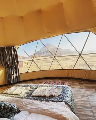 a bed in a room with a large window at Ammar Rum Camp and tours in Wadi Rum