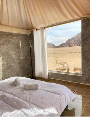 a bedroom with a bed and a large window at Ammar Rum Camp and tours in Wadi Rum