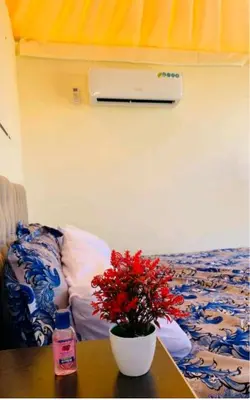a table with a vase of red flowers on a bed at Ammar Rum Camp and tours in Wadi Rum