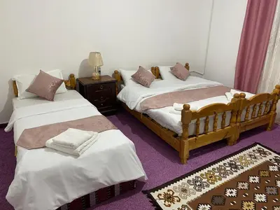 two beds in a room with a purple carpet at Its your choice hostel in Wadi Musa
