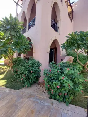 a building with trees and flowers in front of it at Ground floor apartment by circular pool for families only in Talabay in Aqaba