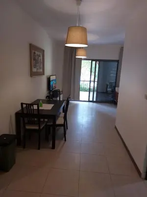 a dining room and living room with a table and chairs at Ground floor apartment by circular pool for families only in Talabay in Aqaba