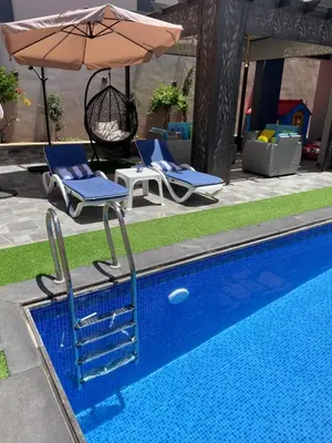 a swimming pool with two chairs and an umbrella at Villa Jana chalet - Private Villa - Dead Sea - Jordan in Ash Shāghūr