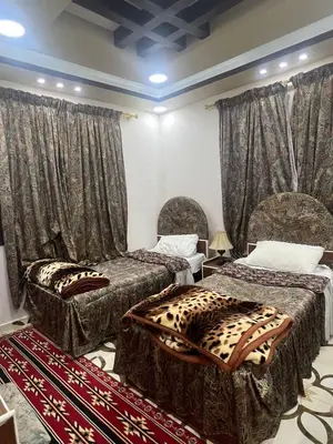 a room with two beds with curtains and a rug at Beida Bedouin House in Al Ḩayy