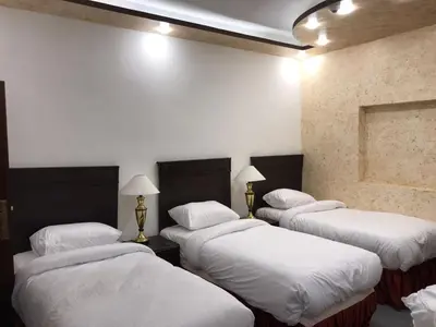 three beds in a room with white walls at ZRIZIRA INN in Wadi Musa