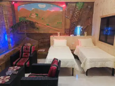 two beds and chairs in a room with a painting at Yaso Roof & Apartments in Amman