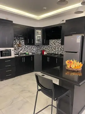 a kitchen with black cabinets and a bowl of fruit on a counter at Aroma Chalet in Sowayma