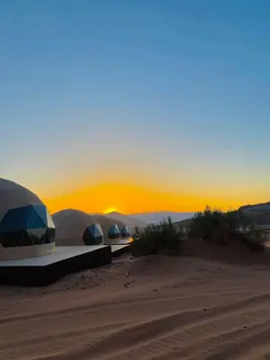 three domes in the desert with the sunset in the background at Syndebad desert camp in Wadi Rum