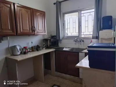 a kitchen with wooden cabinets and a sink and a window at Beit Philodemus in Um Qeis