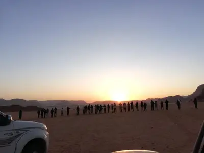 a group of people standing in the desert at sunset at The calm nature of Wadi Rum in Wadi Rum