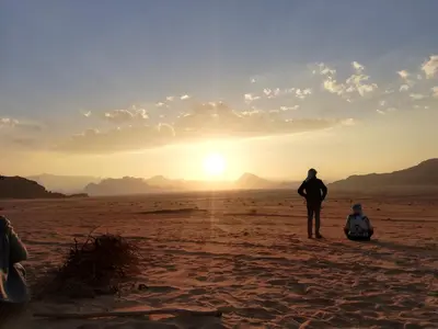 a man standing in the desert watching the sunset at The calm nature of Wadi Rum in Wadi Rum