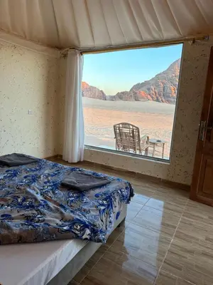 a bedroom with a bed and a large window at Rum Luxury Camp in Wadi Rum