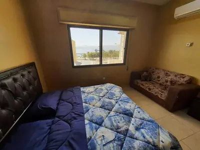 a bedroom with a bed and a couch and a window at العاصم للشقق الفندقية ALASEM HOTEL APARTMENTS in Aqaba
