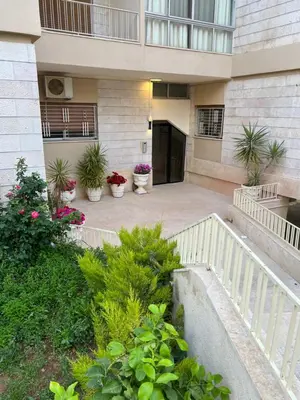 an apartment building with potted plants in a courtyard at Bedouin Break Condo - In the Heart of Amman in Amman