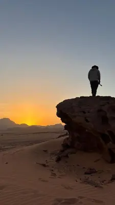 a person standing on top of a rock in the desert at altair luxury rum in Wadi Rum