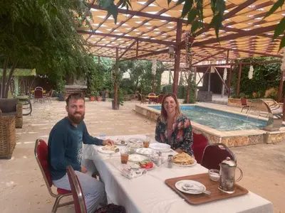 a man and woman sitting at a table in front of a pool at Green houseجوهره الشمال in Ajloun
