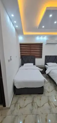 a bedroom with a large white bed with a wooden headboard at Nabateans Home Hotel in Wadi Musa