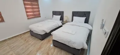 two beds in a small room with white sheets at Nabateans Home Hotel in Wadi Musa