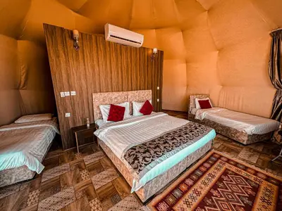 a bedroom with two beds in a room with an orange wall at rum fun luxury camp in Wadi Rum