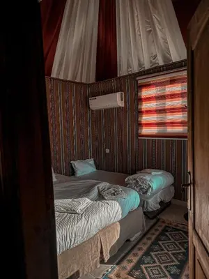 two beds in a small room with a window at rum fun luxury camp in Wadi Rum