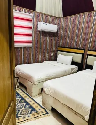two beds in a room with a wall with stripes at Maestro camp Wadi Rum in Wadi Rum