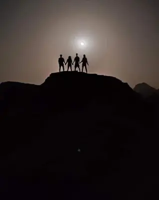 a group of four people standing on top of a mountain at Maestro camp Wadi Rum in Wadi Rum