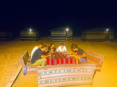 a group of people sitting around a table on the beach at Serenity Camp in Wadi Rum