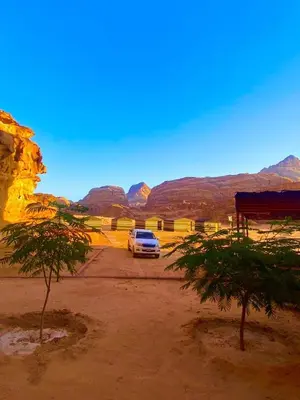 a car parked in a parking lot with mountains in the background at Serenity Camp in Wadi Rum