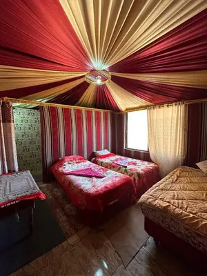 two beds in a room with red curtains at Serenity Camp in Wadi Rum