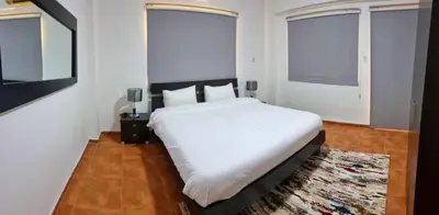 a bedroom with a large white bed and two windows at Byblos Aqaba in Aqaba